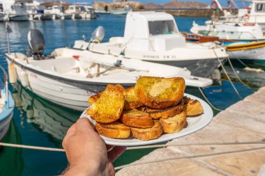 Beyaz tabakta ızgara buğday ekmeği, otlar ve zeytinyağı. Geleneksel Yunan mezeleri. Naoussa, Paros Adası, Yunanistan.