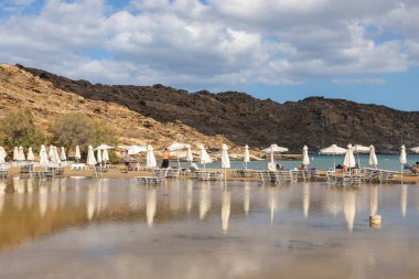 Monasteri Sahili, Paralia, Paros Adası, Yunanistan - 27 Eylül 2020: Paros 'un en popüler plajlarından biri. İnsanlar beyaz şemsiyeler altında güneşleniyorlar..