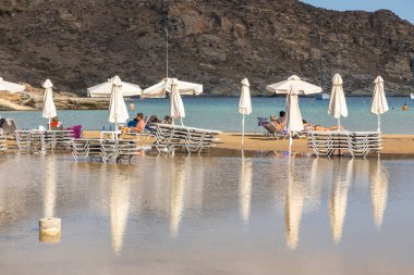 Monasteri Sahili, Paralia, Paros Adası, Yunanistan - 27 Eylül 2020: Paros 'un en popüler plajlarından biri. İnsanlar beyaz şemsiyeler altında güneşleniyorlar..
