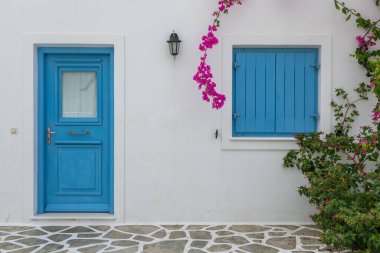 Antiparos Adası 'ndaki popüler tatil beldesindeki beyaz villaların manzarası. Mavi kapı ve fotoğrafçı. Cyclades Takımadası..