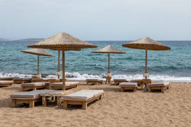 Yunanistan 'ın Antiparos adasında güneşlik ve şemsiyeli kumlu Soros Sahili manzarası. Bulutlu bir gün.