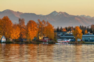 Anchorage, Alaska, ABD - 30 Eylül 2016: Anchorage 'daki Spenard Gölü' nde günbatımının ılık renkleri. Suya park edilmiş küçük bir uçak. Arka planda tepeler.