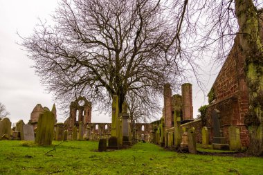 Arbroath, İskoçya, İngiltere - 04 Şubat 2016: Arbroath Abbey 'nin kırmızı tuğla kalıntılarının görüntülenmesi, 1320 tarihli Arbroath Deklarasyonu ile ünlüdür. Mezarlıktaki mezarlar..