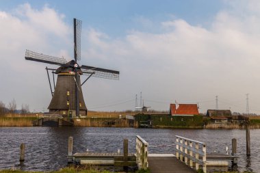 Kinderijk, Hollanda - 11 Mart 2016: Ünlü yel değirmenleri, Lek Kanalı ve küçük iskele manzarası. Müzenin çevresi UNESCO Dünya Mirası Anaokulu.