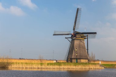 Kinderijk, Hollanda - 11 Mart 2016: Ünlü yel değirmenleri, Lek Kanalı ve küçük iskele manzarası. Müzenin çevresi UNESCO Dünya Mirası Anaokulu.