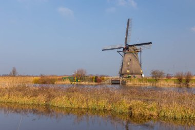 Kinderijk, Hollanda - 11 Mart 2016: Ünlü yel değirmenleri, Lek Kanalı ve küçük iskele manzarası. Müzenin çevresi UNESCO Dünya Mirası Anaokulu.