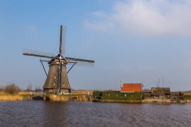 Kinderijk, Hollanda - 11 Mart 2016: Ünlü yel değirmenleri, Lek Kanalı ve küçük iskele manzarası. Müzenin çevresi UNESCO Dünya Mirası Anaokulu.