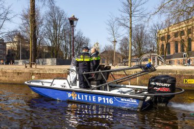 Amsterdam, Hollanda - 12 Mart 2016: Hollanda Polis devriyesi motorlu teknede. Tipik Hollandalı evleri. Şehir görünümü.
