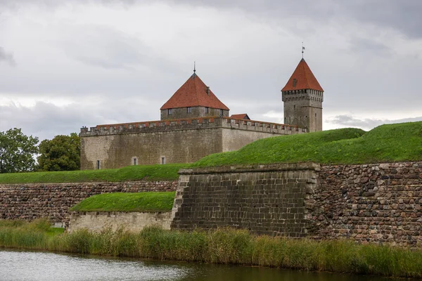 Estonya 'nın Saaremaa adasında hendek ve yeşilliklerle çevrili kırmızı çatılı kuleleri ve taş duvarları olan ortaçağ Kuressaare Kalesi.