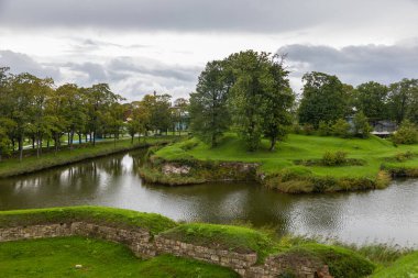 Estonya 'nın Saaremaa kentindeki tarihi Kuressaare Kalesi yakınlarında ağaçlar ve yeşil çimlerle çevrili sakin bir hendek..