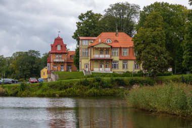 Kuressaare, Saaremaa, Estonya 25 Ağustos 2021: Kuressaare 'de yağmurlu bir günde kırmızı kiremitli ve restoran girişi olan tarihi Arensburg binasının manzarası.