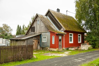 Estonya, Kasepaa 'da sakin bir köy yolu boyunca uzanan kırmızı yüzlü ve yosunlu eski ahşap bir ev..