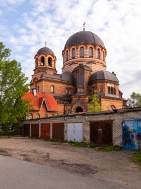 Estonya 'nın Narva kentindeki eski garaj ve kentsel binalarla çevrili koyu kubbeli ve kırmızı tuğladan duvarlı Ortodoks katedrali.