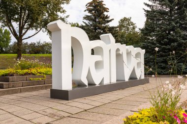 Narva, Estonya, 30 Ağustos 2021: Narva 'da çiçekler, ağaçlar ve kaldırımlarla döşenmiş bir park alanına yerleştirilmiş büyük beyaz şehir işareti.