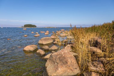 Denizde büyük kaya kütleleri ve Lahemaa Ulusal Parkı 'ndaki Baltık kıyısı boyunca uzanan çimenli bir patikası olan kıyı manzarası. Lahemaa, Estonya.