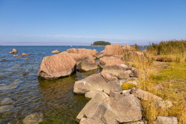 Denizde büyük kaya kütleleri ve Lahemaa Ulusal Parkı 'ndaki Baltık kıyısı boyunca uzanan çimenli bir patikası olan kıyı manzarası. Lahemaa, Estonya.