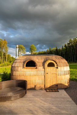 Estonya 'daki Lahemaa Ulusal Parkı' nda akşam güneşinde terasta duran küçük ahşap sauna kulübesi..