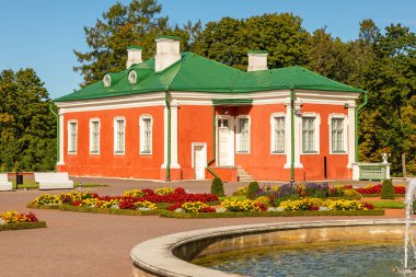 Tallinn, Estonya 'da yeşil çatılı tarihi bir bahçe binası canlı çiçek yataklarının arkasında duruyor. Ön planda bir çeşme havuzu görülebilir..