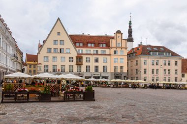 Tallinn, Estonya 2 Eylül 2021: Eski Şehir meydanında renkli tarihi binalar ve açık hava kafelerle çevrili insanlar yürüyor.