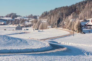 Wygoda Aczynska, Polonya 27 Aralık 2021. Karla kaplı kırsal arazi, donuk ağaçlar, tarlalar ve dolambaçlı kış yolu..