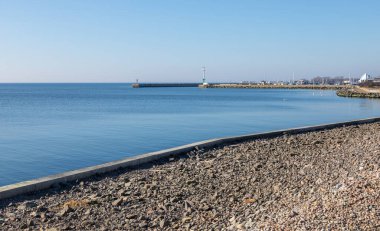 Polonya 'nın başkenti Hel' de taştan kıyı ve liman dalgakıranı olan Baltık Denizi kıyıları. Açık mavi gökyüzü ve sakin deniz manzarası güneşli bir günde.