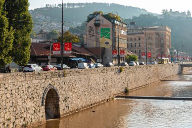 Saraybosna, Bosna-Hersek 15 Ağustos 2022: Arkasında tarihi bir cami ve minare bulunan Bascarsija eski kasabasındaki sokak kafeleri ve geleneksel restoranlar.