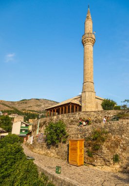 Mostar, Bosna-Hersek, 16 Ağustos 2022: Eski Mostar kentinde tarihi binalarla çevrili Neziraga Camii 'nin taş minaresi.