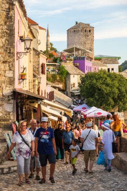 Mostar, Bosna-Hersek, 16 Ağustos 2022. Eski kasabadaki renkli tarihi binaların arasında oturan ve alışveriş yapan insanlar..