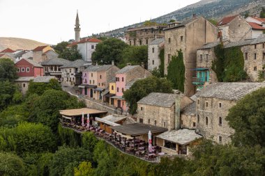 Bosna-Hersek 'in Mostar kenti 17 Ağustos 2022: Eski Mostar kentinde yamaç boyunca tarihi taş evler ve nehir kenarındaki kafeler inşa edildi.
