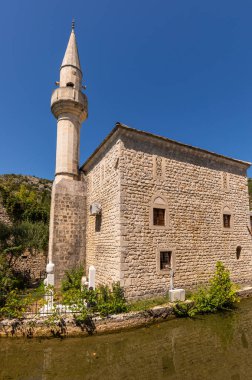 Bosna-Hersek 'in Stolac kentindeki sakin nehir suyuna uzun minareli tarihi taş camii yansıdı.