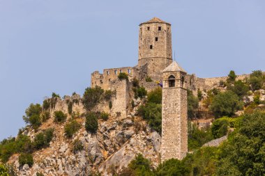 Pocitelj, Bosna ve Hercegovina - 18 Ağustos 2022: Capljina, Bosna-Hersek 'e tepeden bakan tarihi Pocitelj kalesi ve saat kulesi.