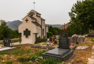 Prhinje, Bosna ve Hercegovina - 19 Ağustos 2022: Velicani mezarlığında küçük bir Ortodoks şapeli, mezar taşları ve çevre doğa yer alıyor.