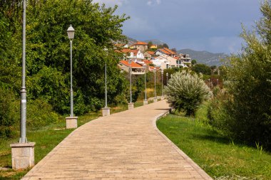 Bosna-Hersek 'in Trebinje kentindeki yeşil bir yamaçtaki konut binalarına doğru giden dönemeç yol..