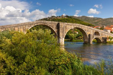 Arslanagica Most, Bosna-Hersek 'in beyaz bulutlarıyla mavi gökyüzünün altındaki Trebisnjica Nehri' ni kaplayan bir Osmanlı kemer köprüsü..