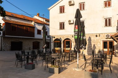 Trebinje, Bosna ve Hercegovina - 21 Ağustos 2022: Eski taş binalar ve açık kafeler minareli sakin bir kaldırım kaldırımı hattı.