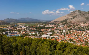 Trebinje, Bosna ve Hercegovina - 21 Ağustos 2022: Trebinje şehir binaları ve açık mavi gökyüzü altındaki yeşil ağaçlar.