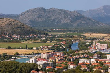 Trebinje, Bosna ve Hercegovina - 21 Ağustos 2022: Trebinje şehri, güneşli bir dağ vadisinde çatılar ve ağaçlar.