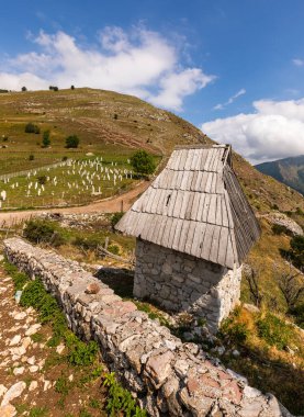 Lukomir, Konjiç, Bosna-Hersek 'te mezarlığın yanındaki yamaçtaki geleneksel taş ev..