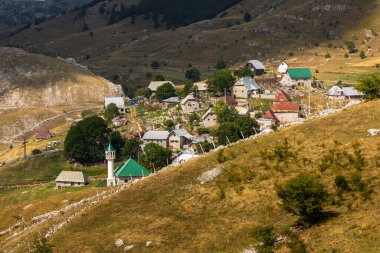 Lukomir, Bosna ve Hercegovina - 22 Ağustos 2022: Bir dağ sırtında duran kişi bulutlu bir gökyüzünün altındaki geniş dağ manzarasına bakıyor.