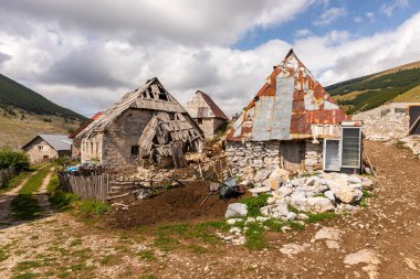 Lukomir, Bosna ve Hercegovina - 22 Ağustos 2022: Bir dağ sırtında duran kişi bulutlu bir gökyüzünün altındaki geniş dağ manzarasına bakıyor.