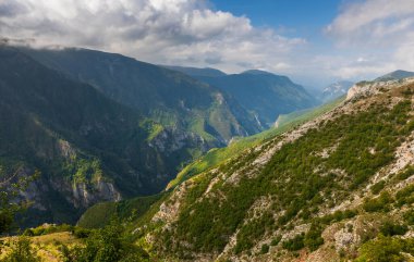 Geniş, yeşil vadileri, kayalık yamaçları ve Bosna-Hersek 'in Lukomir kenti yakınlarındaki bulutlu gökyüzü ile Dinarik Alp Dağları manzarası.