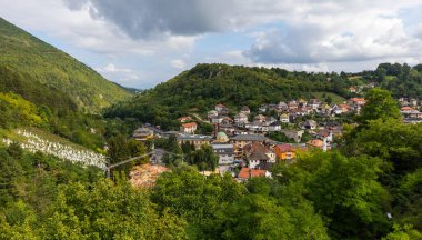 Travnik, Bosna ve Hercegovina - 24 Ağustos 2022: Yeşil dağlarda yuva yapmış gezgin kasaba, cami kubbesi ve mezarlığı gösteriyor.