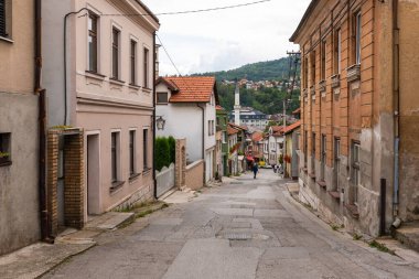 Travnik, Bosna ve Hercegovina - 24 Ağustos 2022: Geleneksel evleri ve uzak bir cami minaresi olan eski Varos Caddesi.
