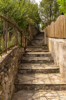 Metal bir çitle yokuş yukarı giden ahşap çitler arasındaki taş adımlar, Bosna-Hersek 'in Jajce kentinde ilerleme yolunu gösteriyor..