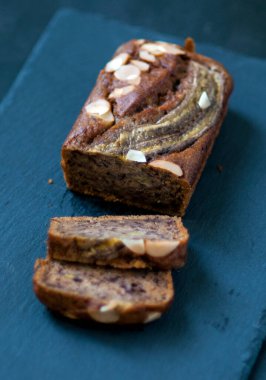 Koyu arkaplanda badem dilimleri olan muzlu pasta.