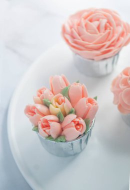 Pembe tereyağlı beyaz masada kırmızı kadife kekler.