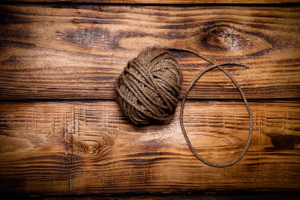 Rope hank on old wooden burned table or board for background. To — Stock Photo, Image