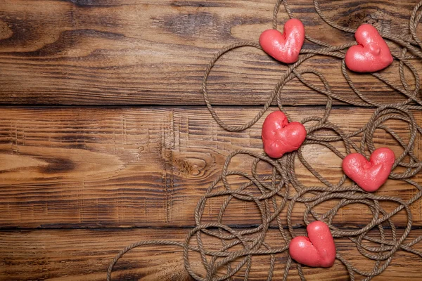 Cuerda y corazones rojos en una vieja mesa o tablero quemado de madera para la espalda — Foto de Stock