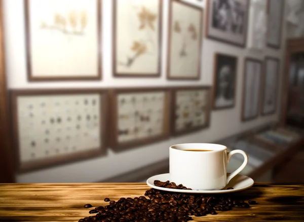 Caffè in una tazza sul tavolo in legno di fronte a un interio sfocato — Foto Stock