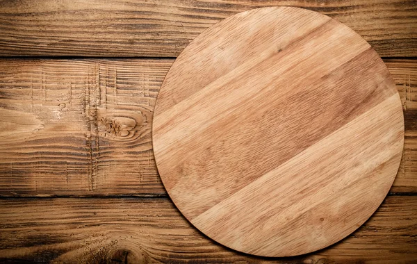 Round cutting board on old wooden burned table or board for back — Stock Photo, Image